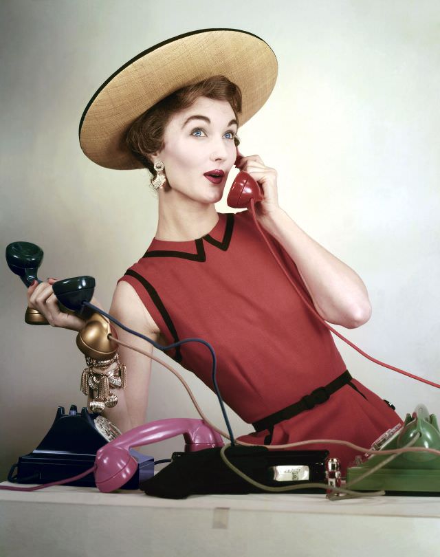 #22 Evelyn Tripp wearing red sleeveless linen dress by Larry Aldrich, and black-rimmed straw boater, Vogue, April 1953