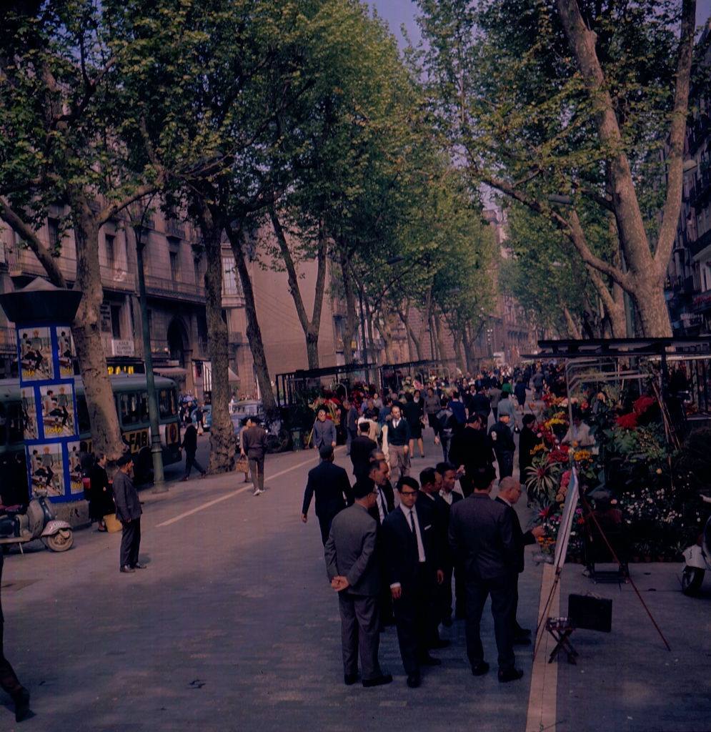 #27 View of a street scene with florist stalls and a street artist in Barcelona, 1966.