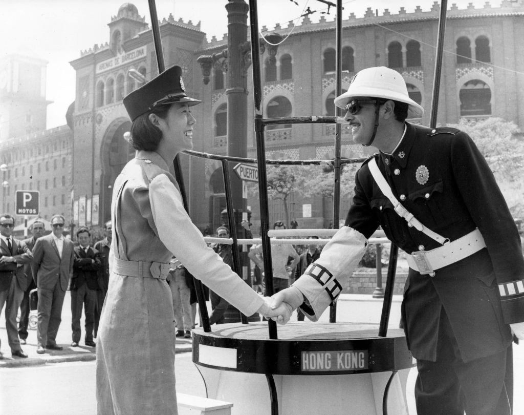 #59 A policewoman from Hong Kong shakes hands with a Spanish policeman at the International Samples Fair in Barcelona, 1966.