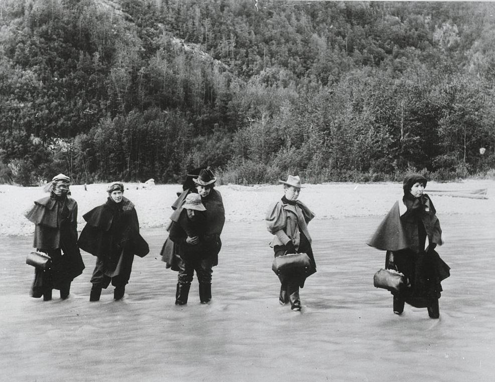 #37 A man carries an actress across an Alaskan river while others must ford it to get to a gold mine, 1897.