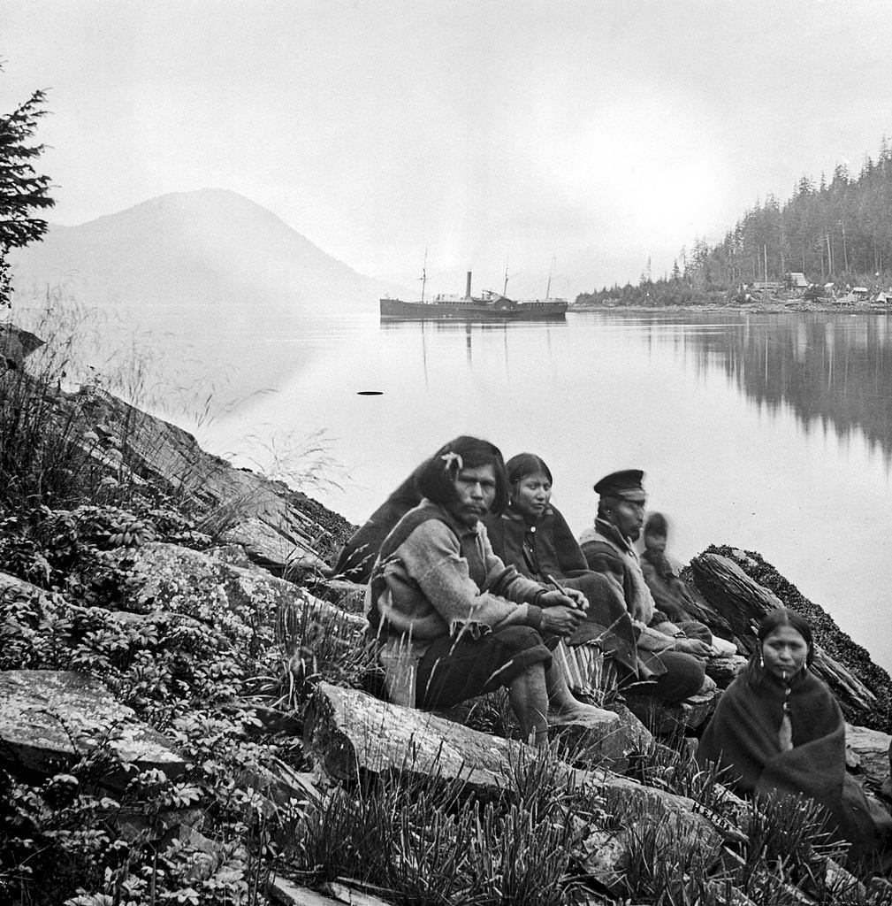 #16 Amerindian family sitting beside a waterway, Alaska, 1868.