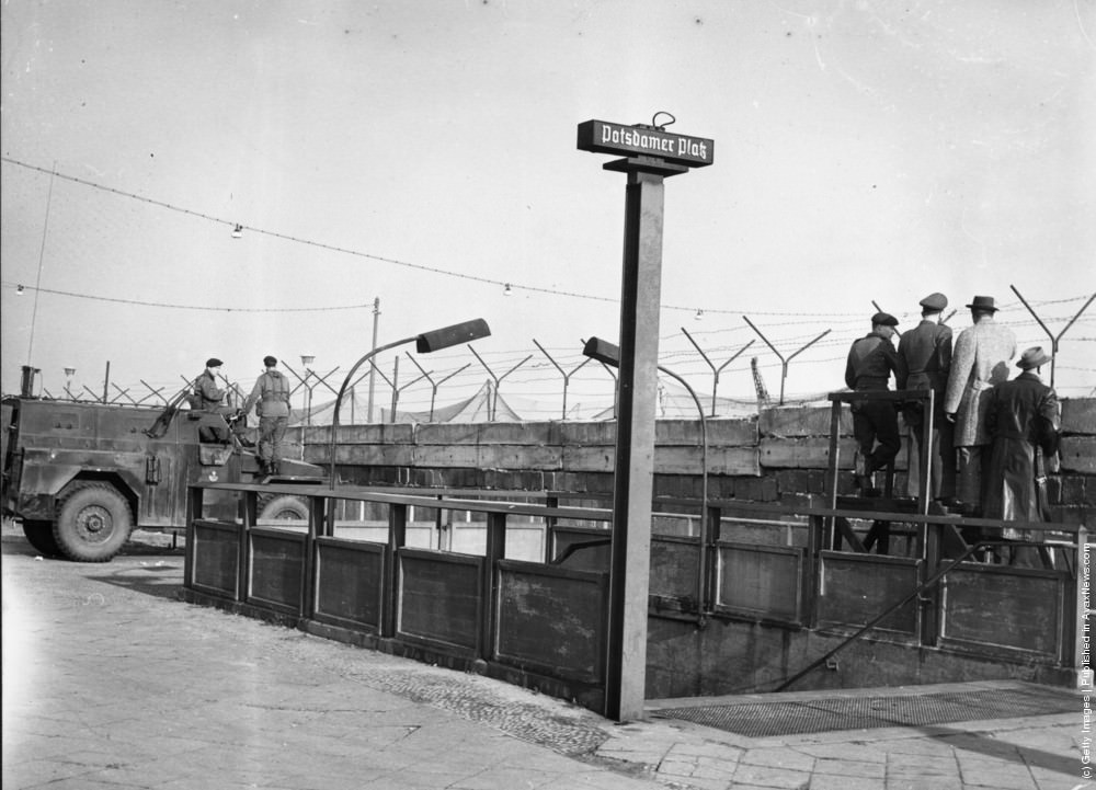Soldiers outside the entrance to Berlin’s Potsdamer Platz underground station next to a section of the Berlin Wall, circa 1961.