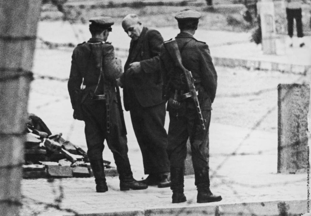 Members of the Volkspolizei, the East German national police, check an elderly man’s papers at the Berlin Wall, 11th September 1961.