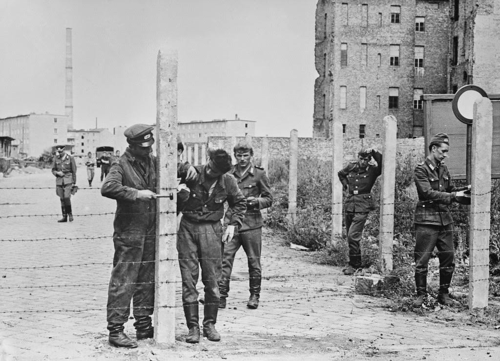 Soldiers of the East German National People’s Army (NVA) erecting barbed wire fences to close off a street in preparation for the construction of the Berlin Wall, Berlin, Germany, 14th August 1961.