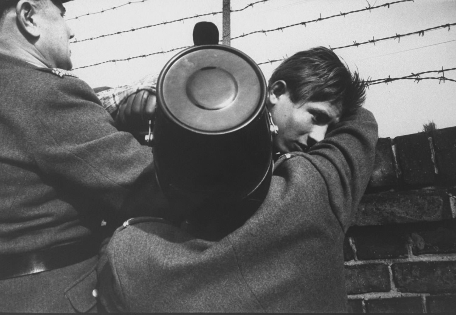 #87 A 17-year-old East German orphan successfully slips through the barbed wire over the Berlin Wall to the West after being waved on by West Berlin police in October 1961.