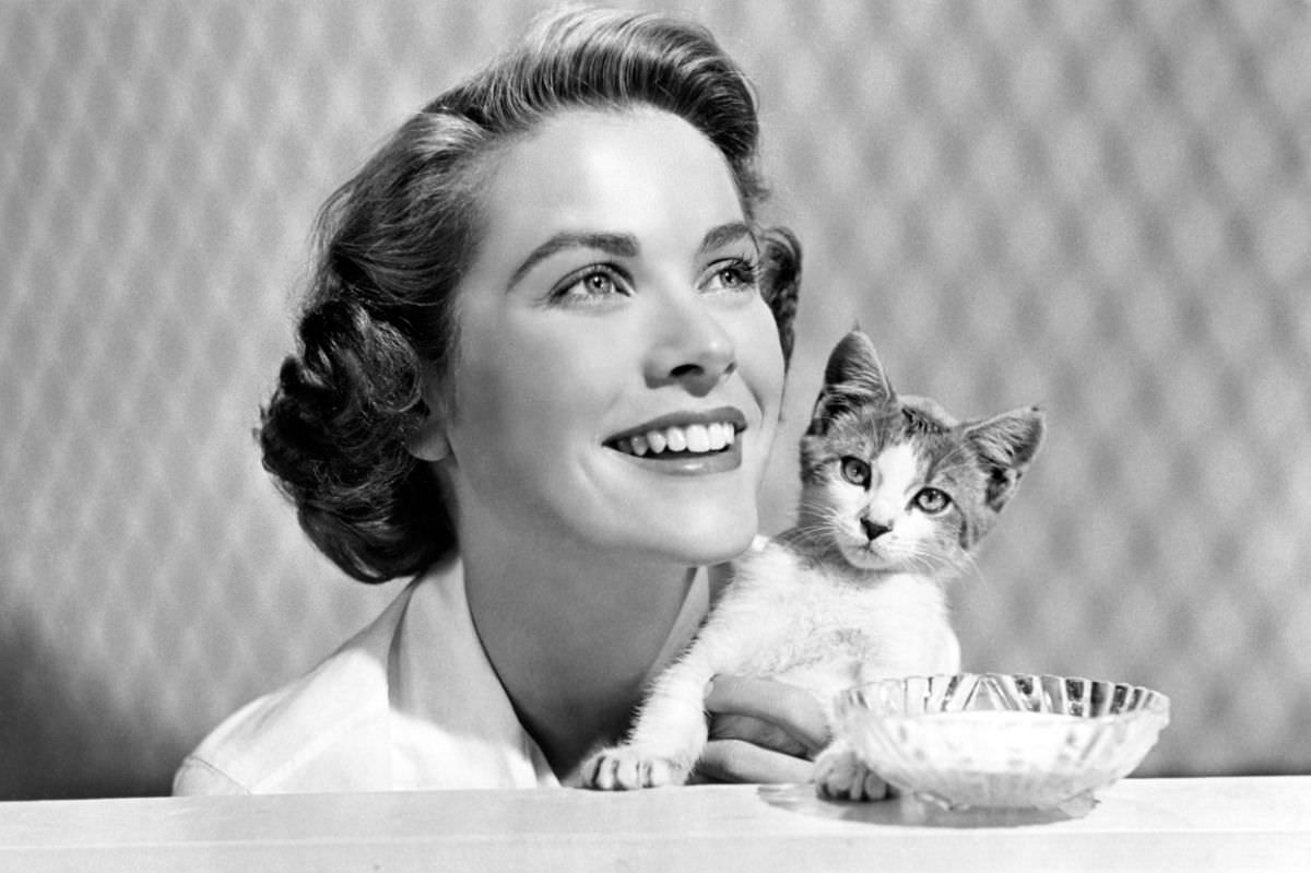 #9 Grace Kelly clutching a kitten while working as a part-time model, some eight years before she would become the Princess of Monaco, 1944.