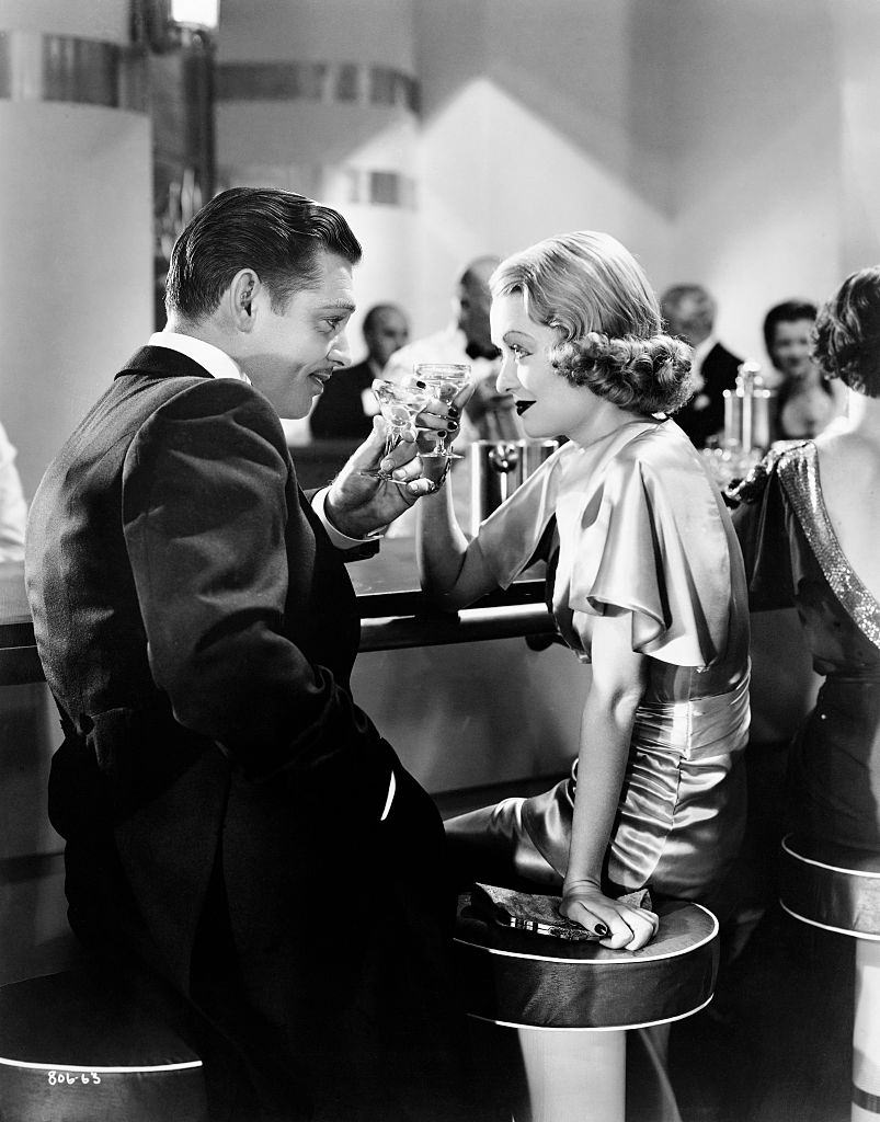 #70 Constance Bennett with Clark Gable toast in a scene from the 1935 film, After Office Hours.