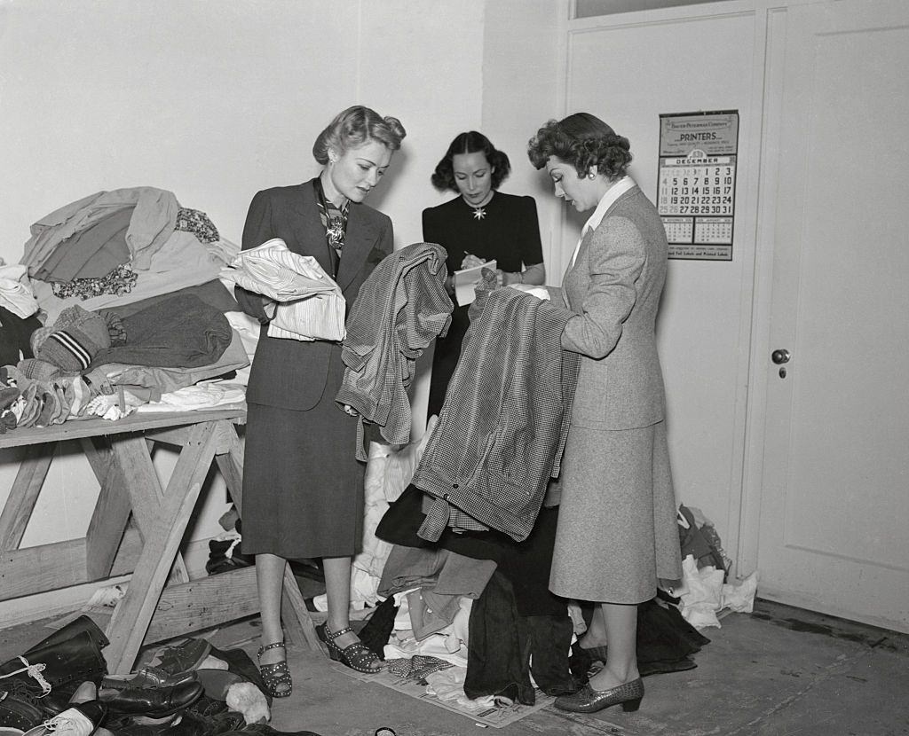#4 Constance Bennett with Dolores Del Rio and Claudette Colbert inspecting clothing at the Hollywood headquarters of the International Committee for refugees in France, 1940.
