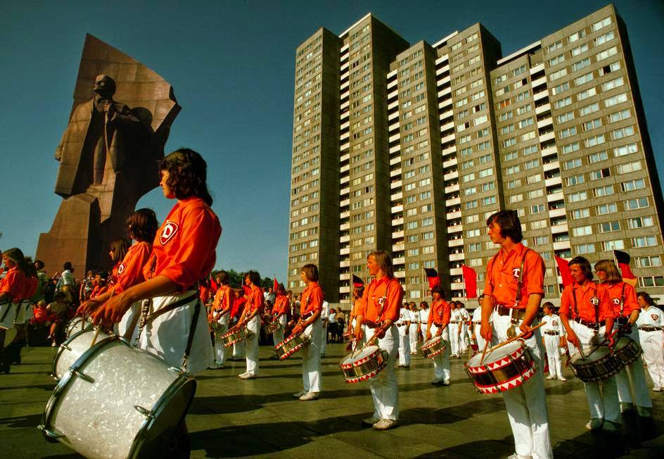 #9 A Free German Youth Organization band plays at a Lenin Statue in front of new concrete buildings. East Berlin, 1974.