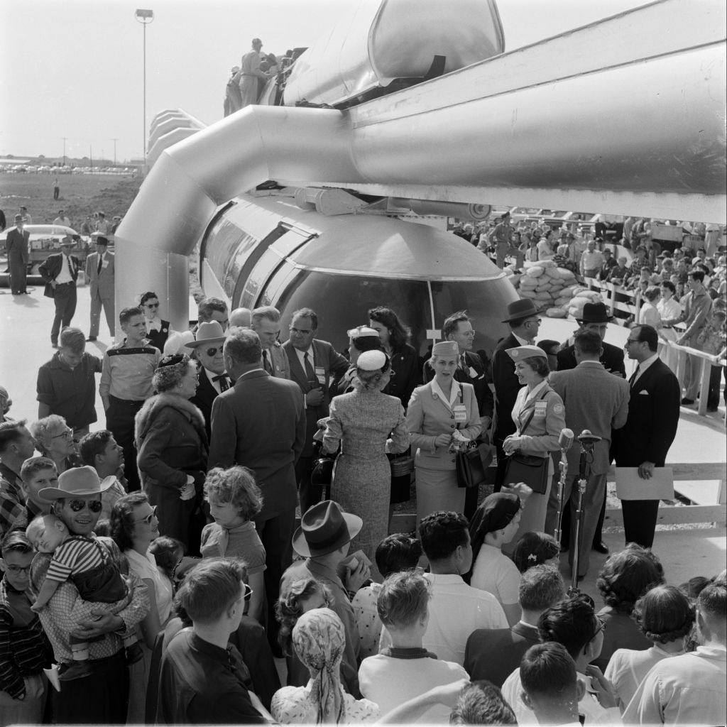 #56 People gathering near a monorail train, Houston, 1956.