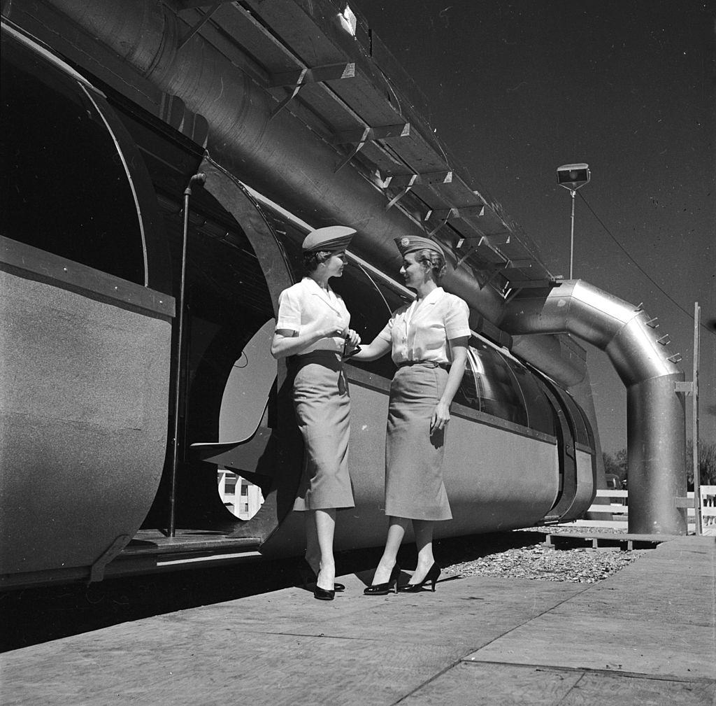 #9 Two hostesses stand in front of a new monorail service in Houston, 1950s.
