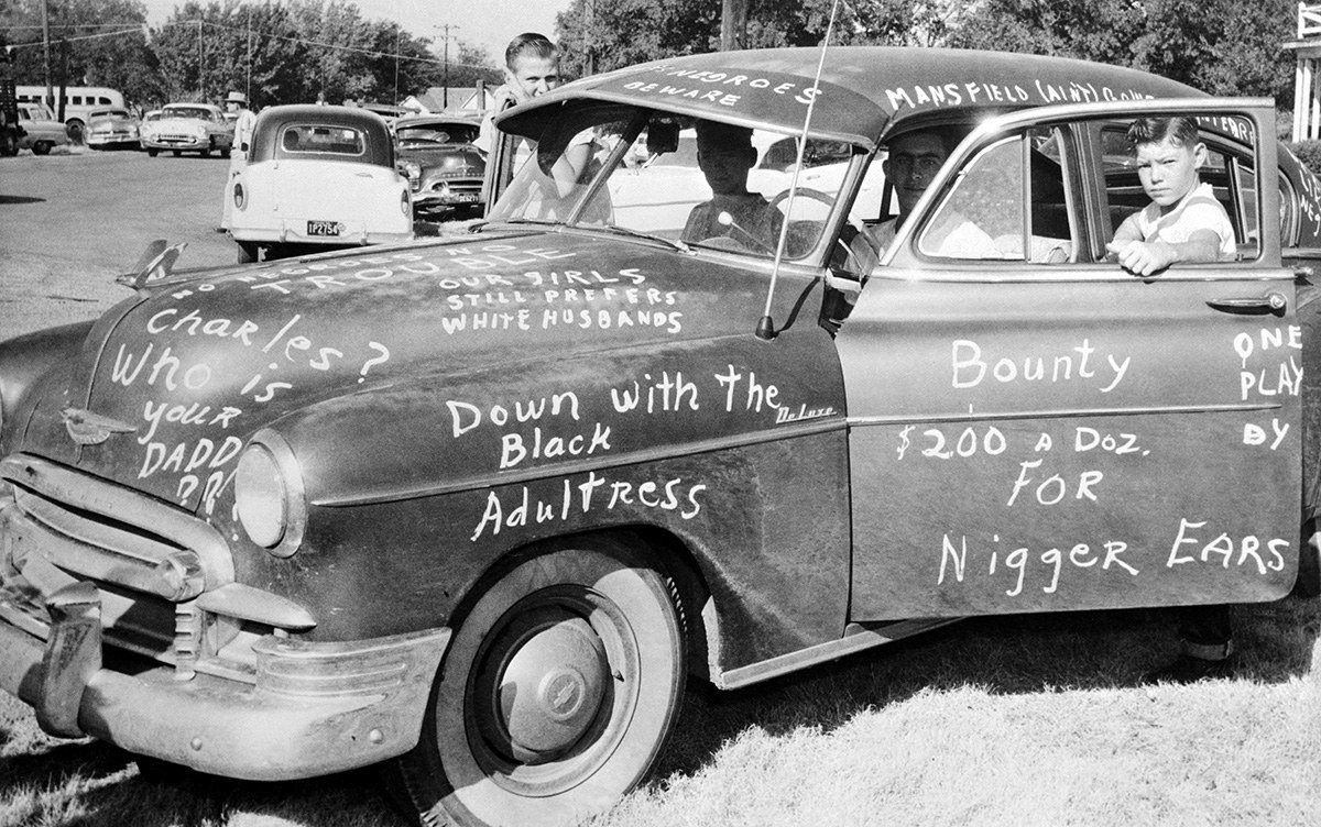 #30 Roy Lee Howlett, 14, stands beside a car painted with signs protesting the desegregation of Mansfield High School in Dallas on Aug. 31, 1956.