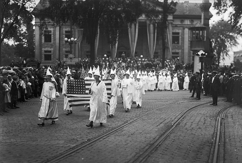 #53 Female Ku Klux Klan members march through Binghamton, NY holding an American flag in the 1920s.