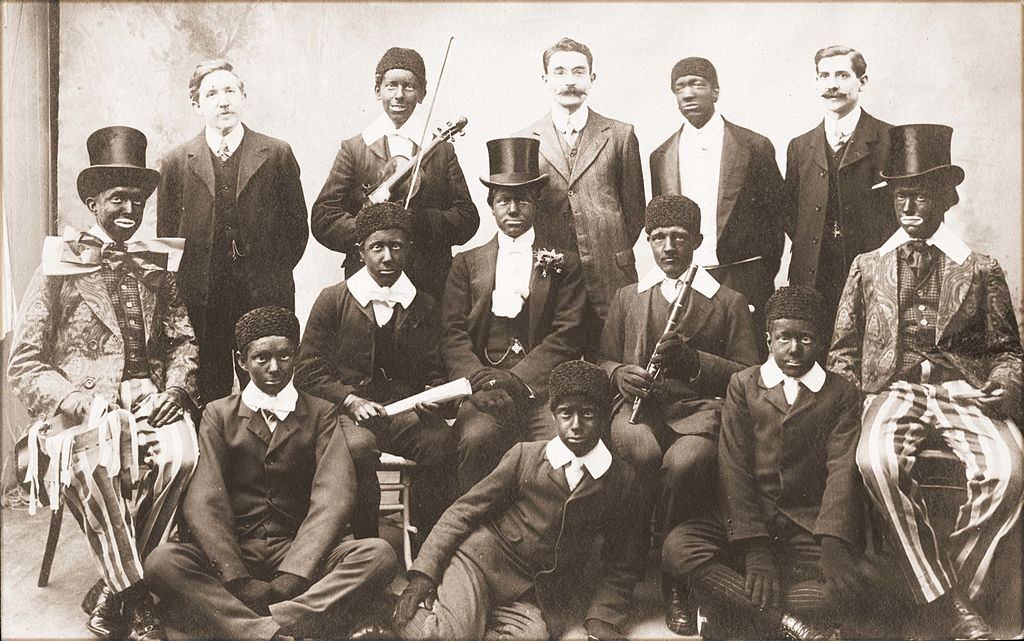 #55 Ten young men in costume and blackface, members of a minstrel troupe, pose with three others in street clothes,1910.