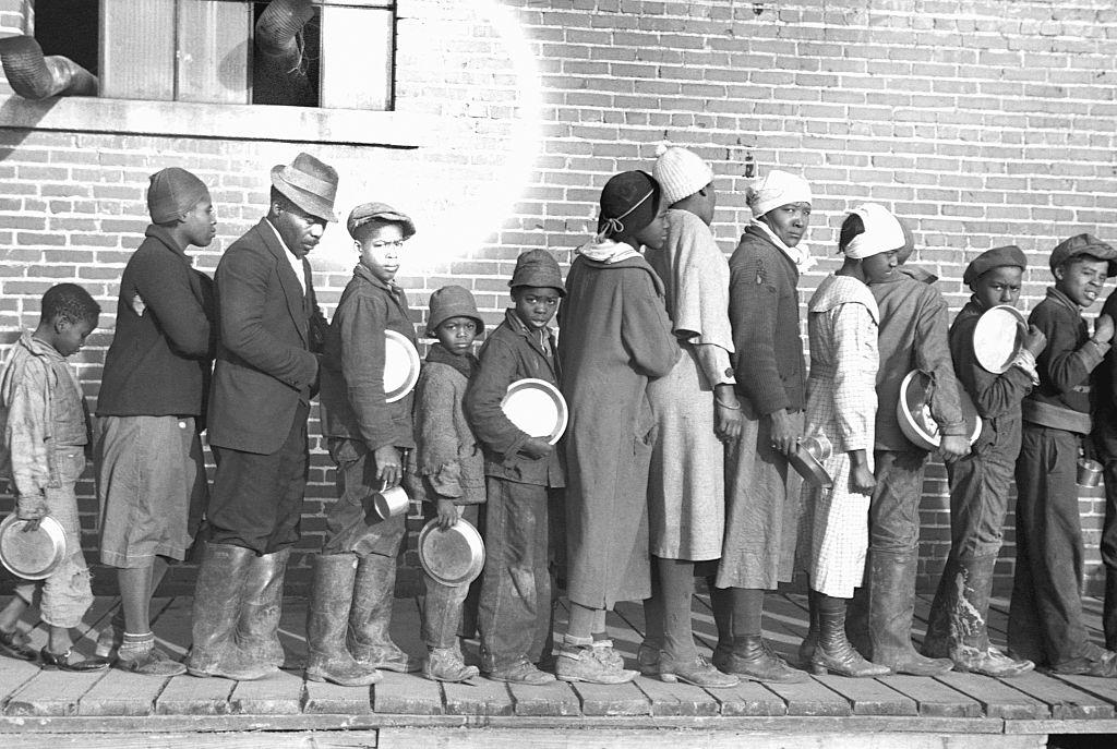 #66 Flood refugees lined up and waiting for food at a temporary camp for African Americans. Forrest City, Arkansas, February 1937.