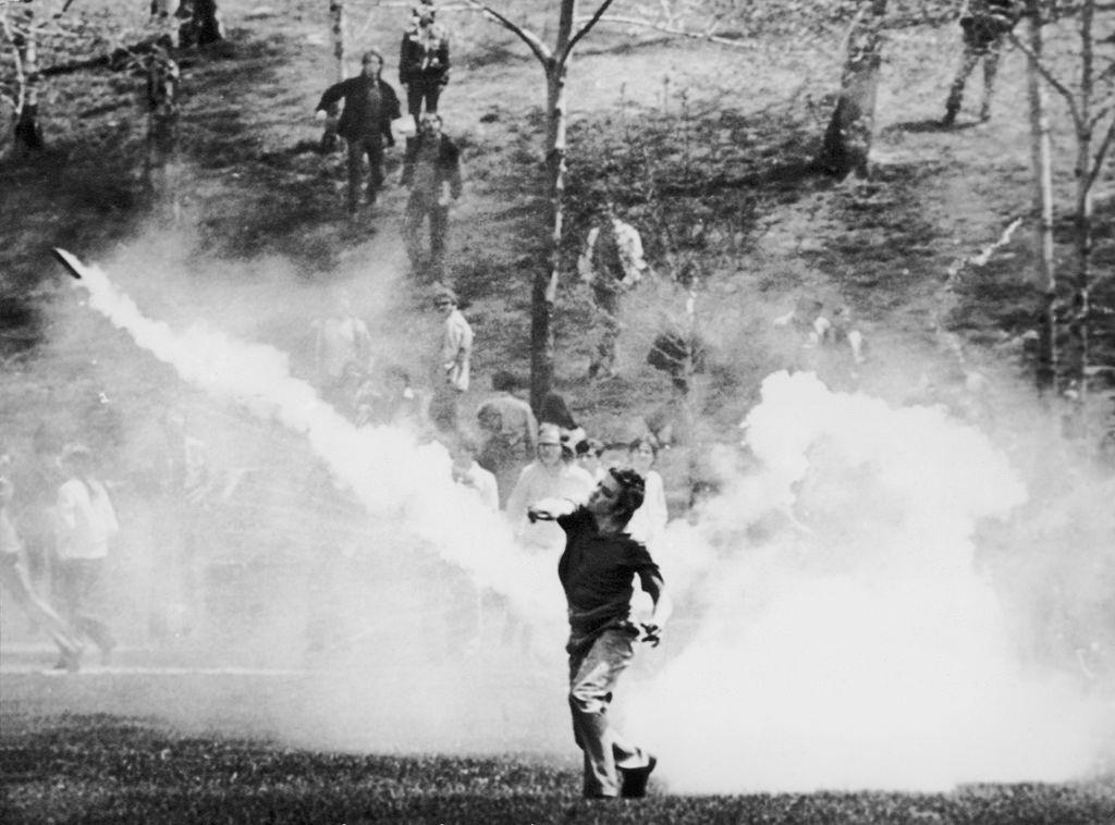 #13 A student throws a tear gas canister back at National Guardsmen during a demonstration, 4th May 1970.