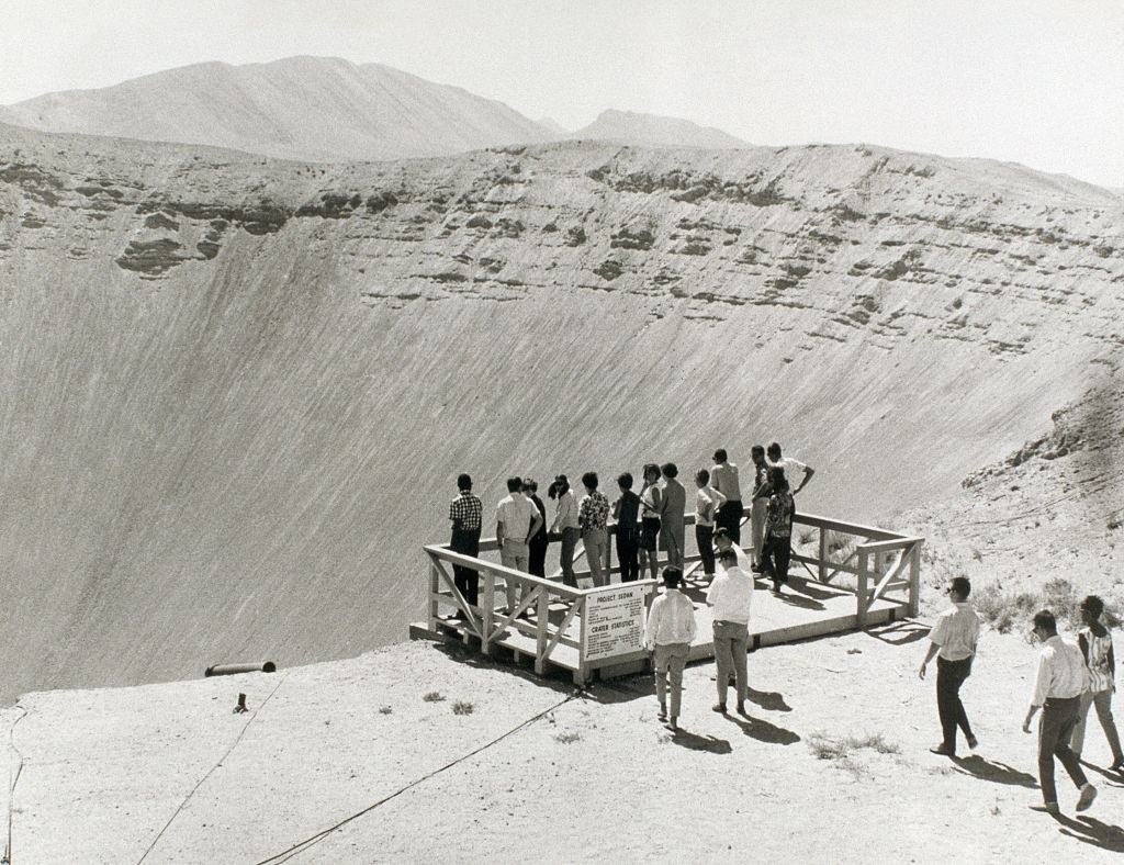#21 People stand at the edge of a gigantic crater created by the Project Sedan nuclear test explosion, 1950s.