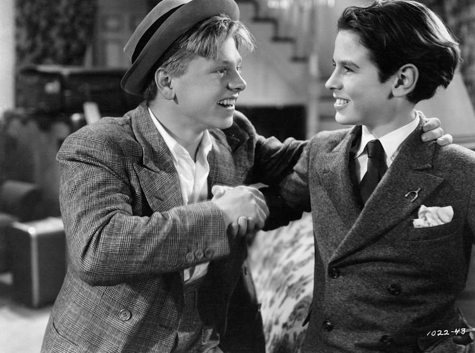 #33 Mickey Rooney shaking Ronald Sinclair’s hand in a scene from the film ‘Thoroughbreds Don’t Cry’, 1937.