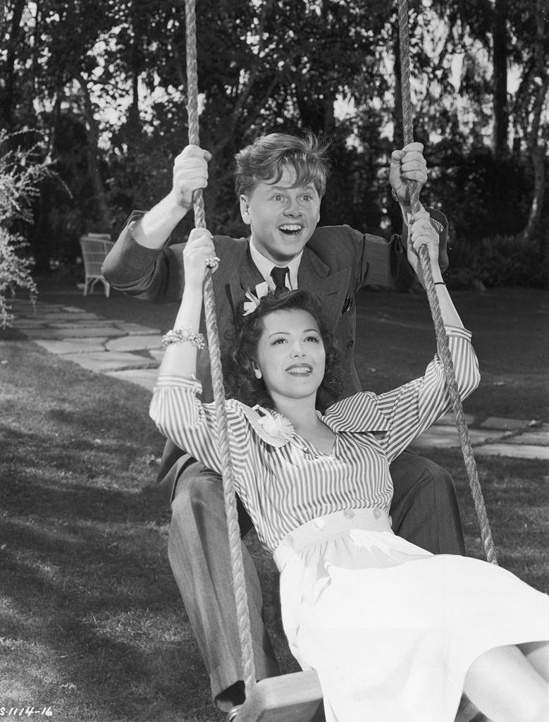 #52 Mickey Rooney with Ann Rutherford smile as they share a swing together, 1939.