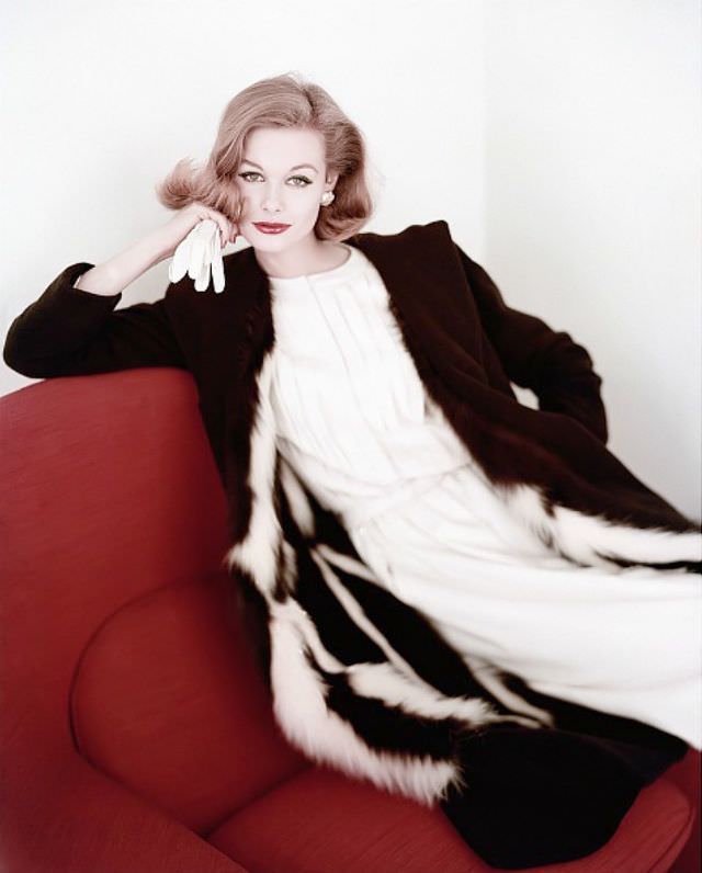 #3 Monique Chevalier in chocolate brown wool coat lined in skunk fur worn over a white worsted pleated dress, Vogue. October 15, 1958