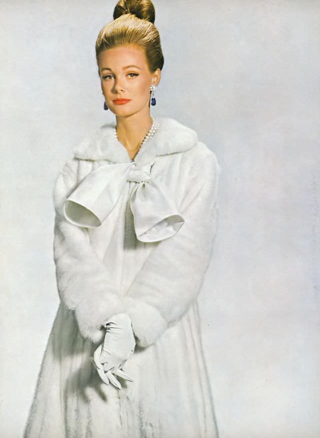 #25 Monique Chevalier in Jasmine EMBA white mink coat-dress, white satin tie and zipped closing in front, Vogue. October 1, 1963.