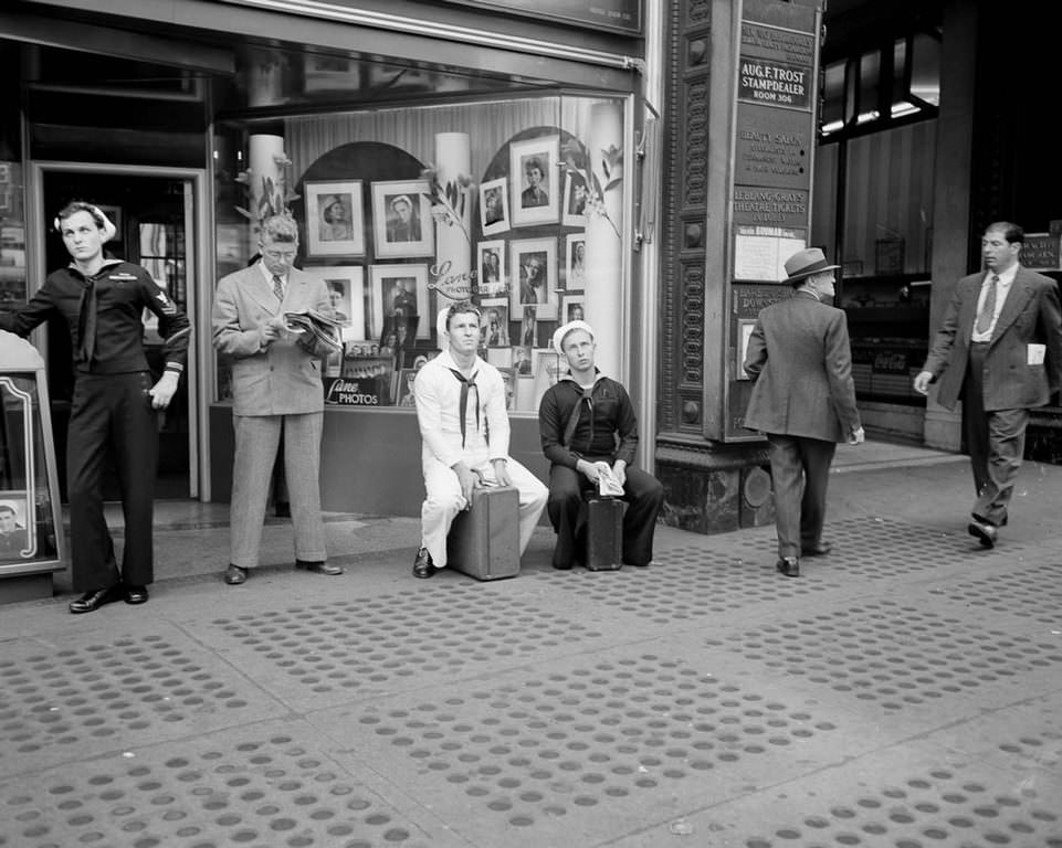 Sailors sit on their briefcases and lean against door frames as they wait for more news in one of the most significant developments of World War Two.