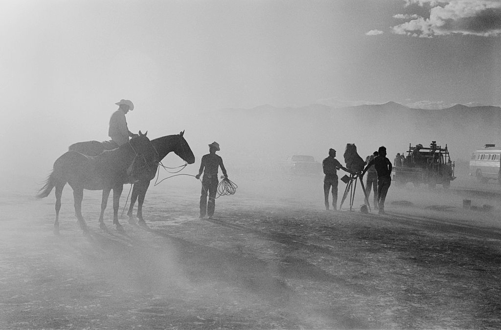 A man riding a horse while a camera is set up for a scene in ‘The Misfits’, filming on location in the Nevada Desert.