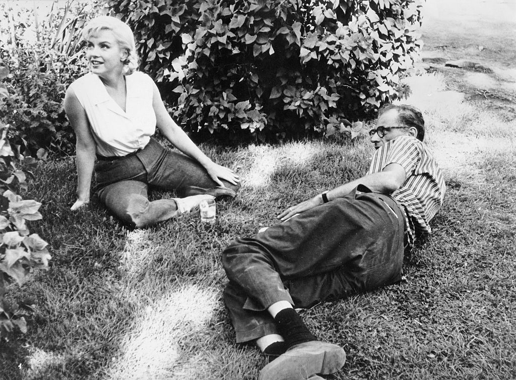 Marilyn Monroe with her husband Arthur Miller, sitting on a meadow during a break in filming ‘The Misfits’