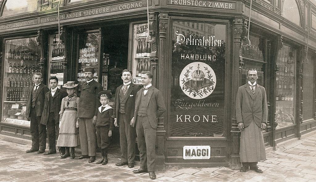 #37 Delicatessen salesmen with his employees in front of his delicatessen shop entitled “Zur goldenen Krone” in Vienna, 1900.