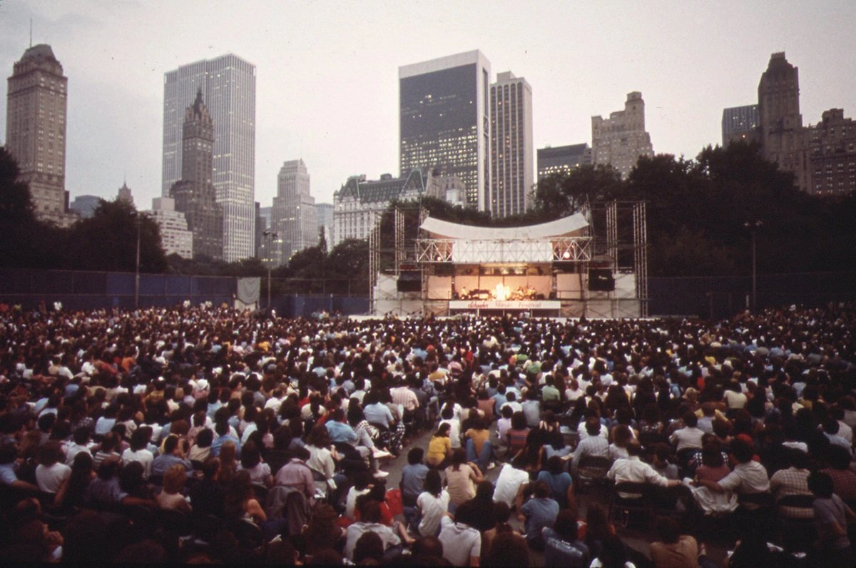 #31 Crowd gathered at the Schaefer Bandstand in Central Park to hear singer Judy Collins with a dramatic view of the towers of midtown Manhattan in June of 1973.