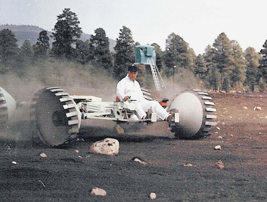 #5 A Grumman Aircraft Engineering Corporation lunar-rover concept vehicle navigates boulders with a Grumman engineer driving.