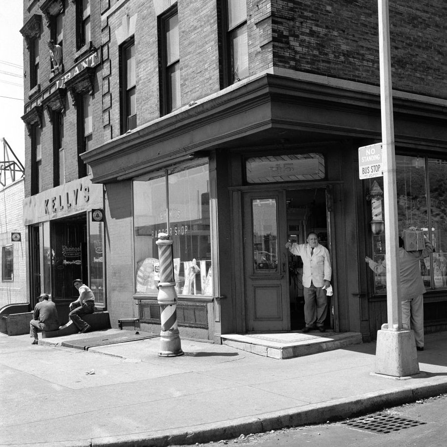 #20 Barber Jerry talks to a delivery man outside Jerry’s Barber Shop, at 15 Atlantic Avenue in Brooklyn Heights, March 1958.