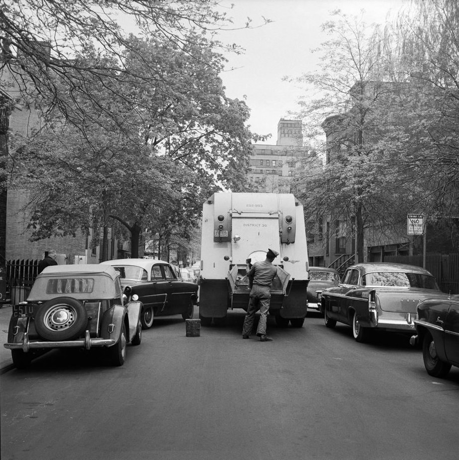 #21 A sanitation worker collects garbage in Brooklyn Heights, 1958.