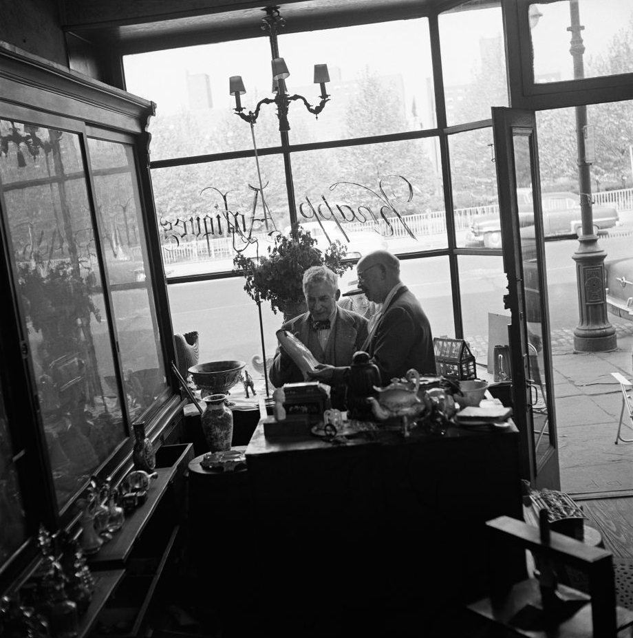 #60 Legendary antiques dealer George Knapp, a subject of author Truman Capote, helps a customer at Knapp Antiques, at 224 Fulton Street in Brooklyn Heights, March 1958.