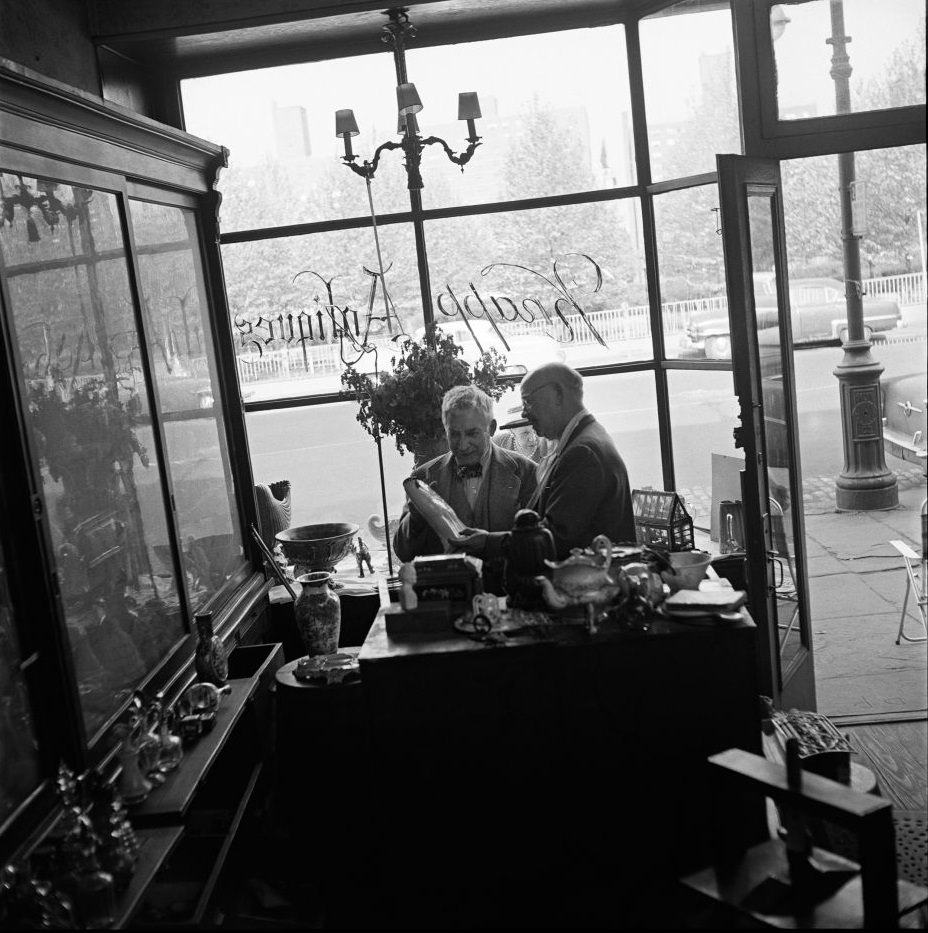 #68 Legendary antiques dealer George Knapp, a subject of author Truman Capote, helps a customer at Knapp Antiques, at 224 Fulton Street in Brooklyn Heights, March 1958.
