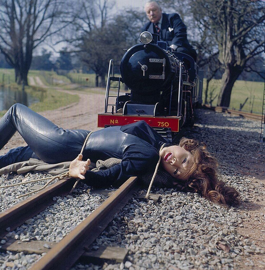 #49 Diana Rigg as ‘Emma Peel’ is tied to a railway track as a miniature train advances on her in a scene from the television series ‘The Avengers’ in 1968.