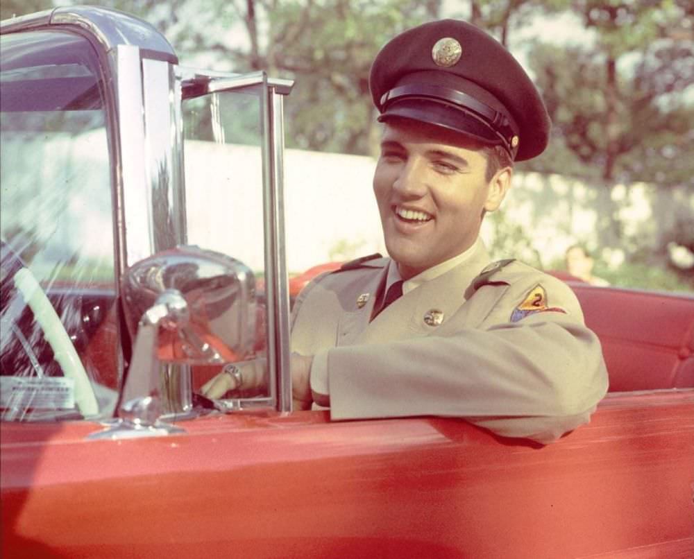 #5 Elvis sits behind the wheel of a red car, returning home for two weeks after basic training in June of 1958.