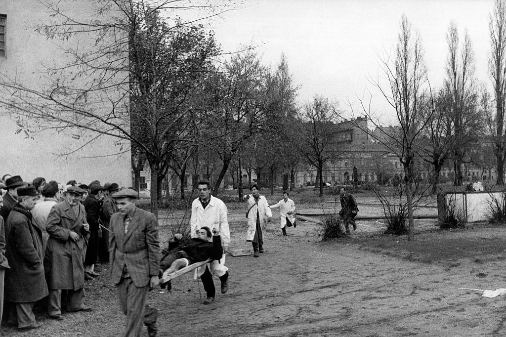 #17 A wounded man is led to safety during the revolt. Budapest, November 1956
