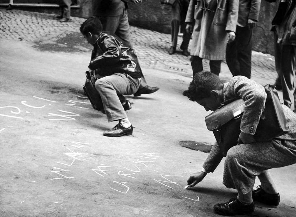 #32 Students writing on the ground some solidarity messages to the rebels in Hunary after the repression by Soviet Tanks, 1956.