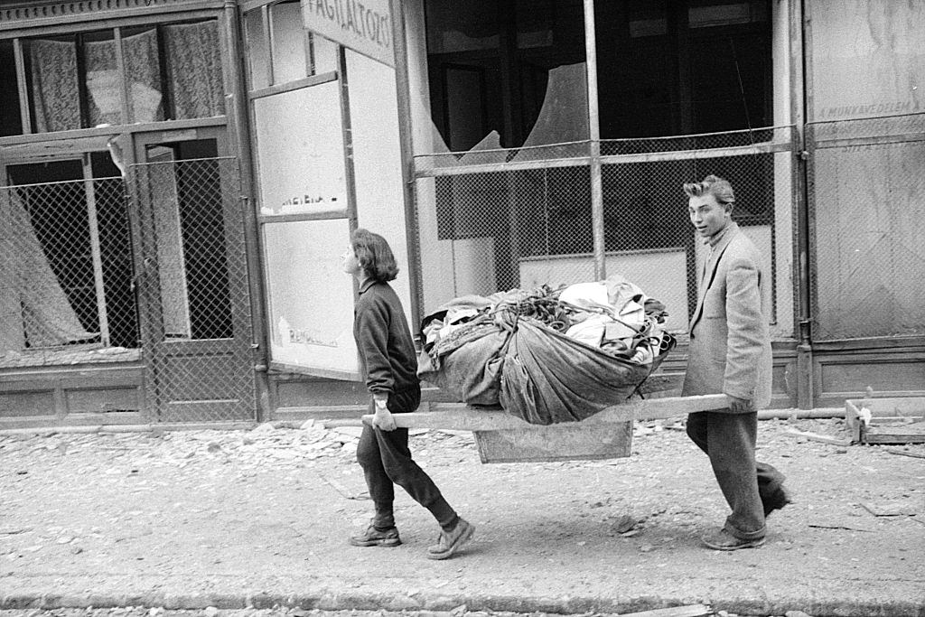 Two people carrying their things across the ruins of the city. Budapest, 29th October 1956.