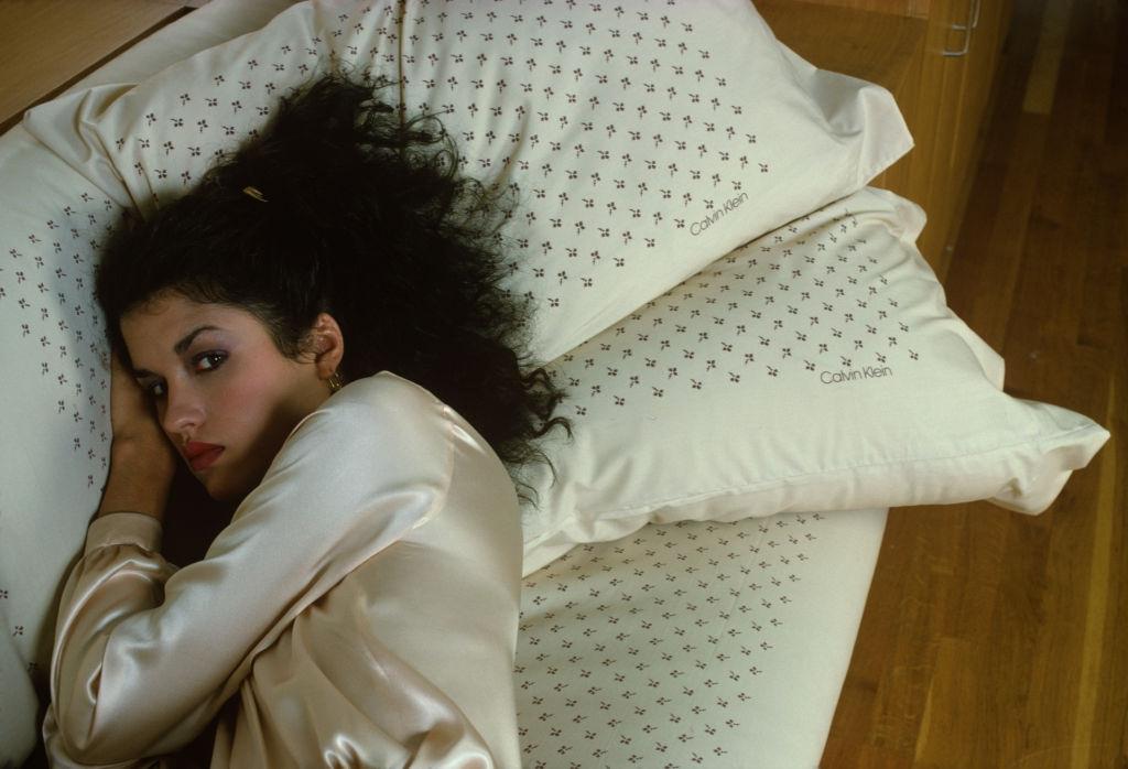 #17 Janice Dickinson dressed in a silk gown, as she lies on a sofa, 1978.