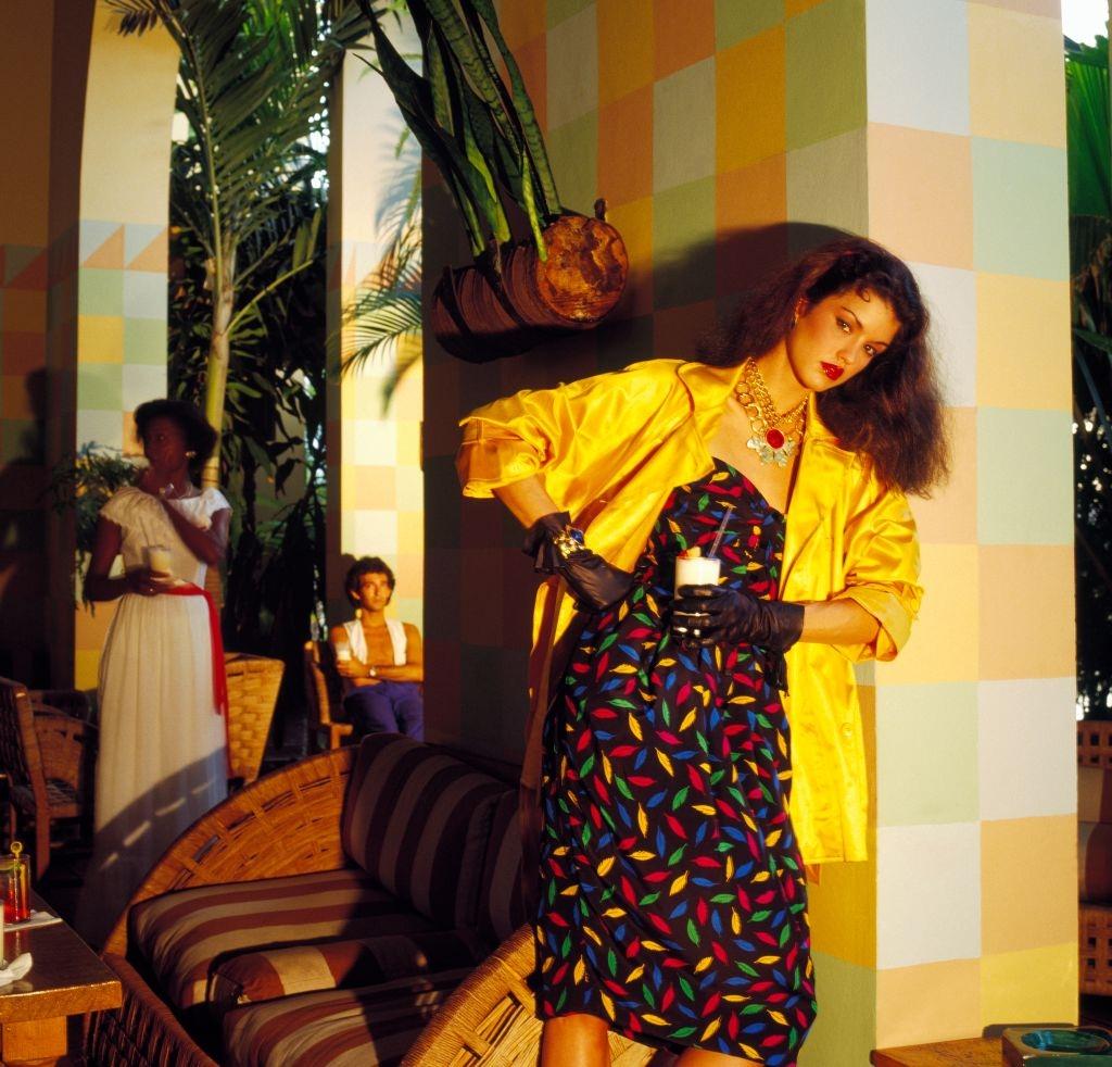 #22 Janice Dickinson wearing a colorful print cocktail dress with a yellow satin jacket, 1979.
