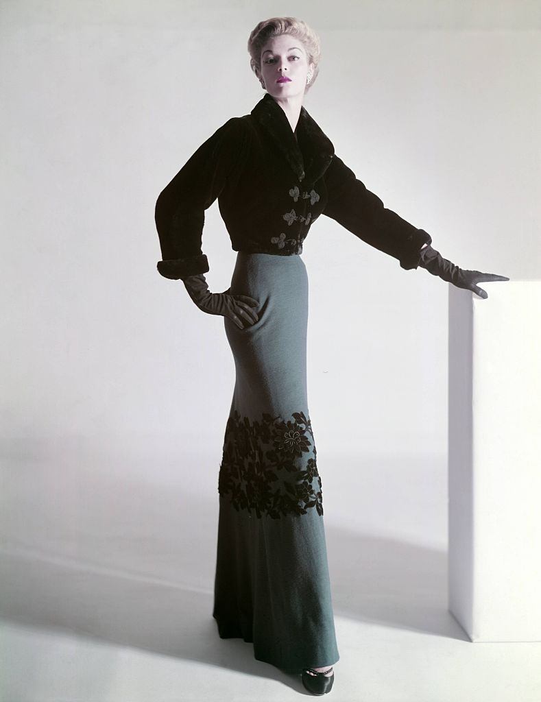 #25 Jean Patchett in a sealskin Mainbocher jacket and floor-length skirt with velvet flowers at the knee, 1951.