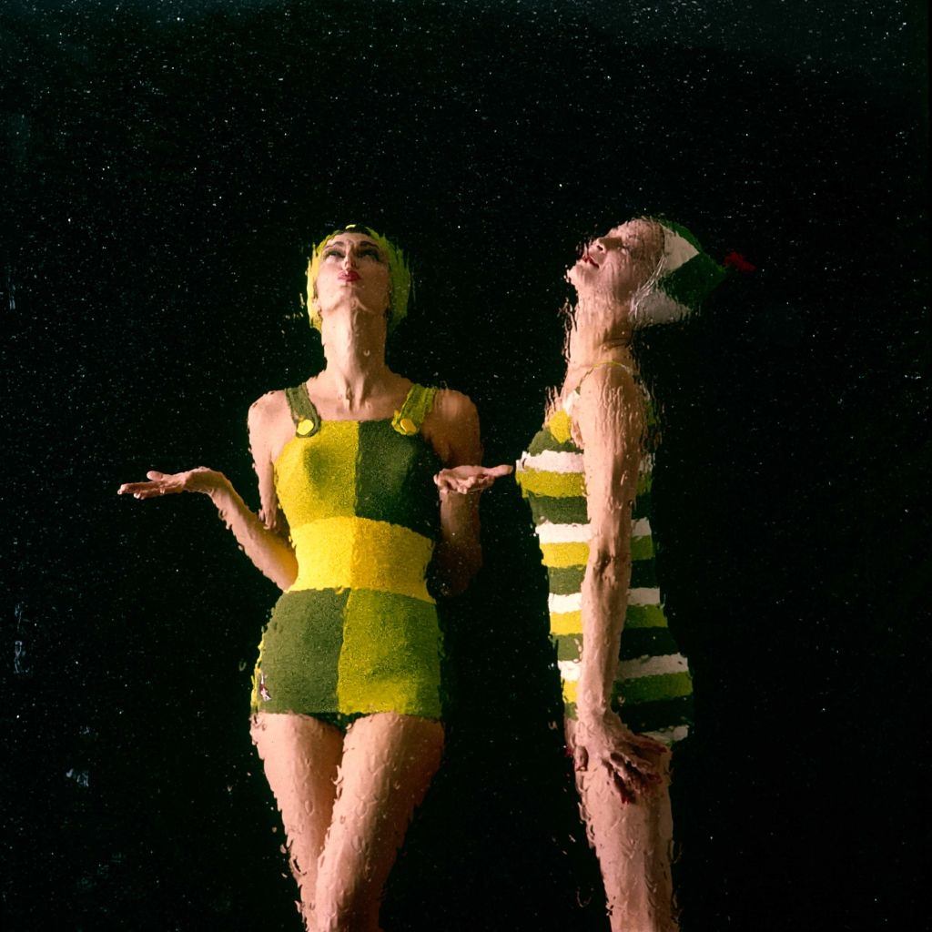 #35 Jean Patchett n a yellow, green, and white striped swimsuit and matching swim cap with another model, 1960.