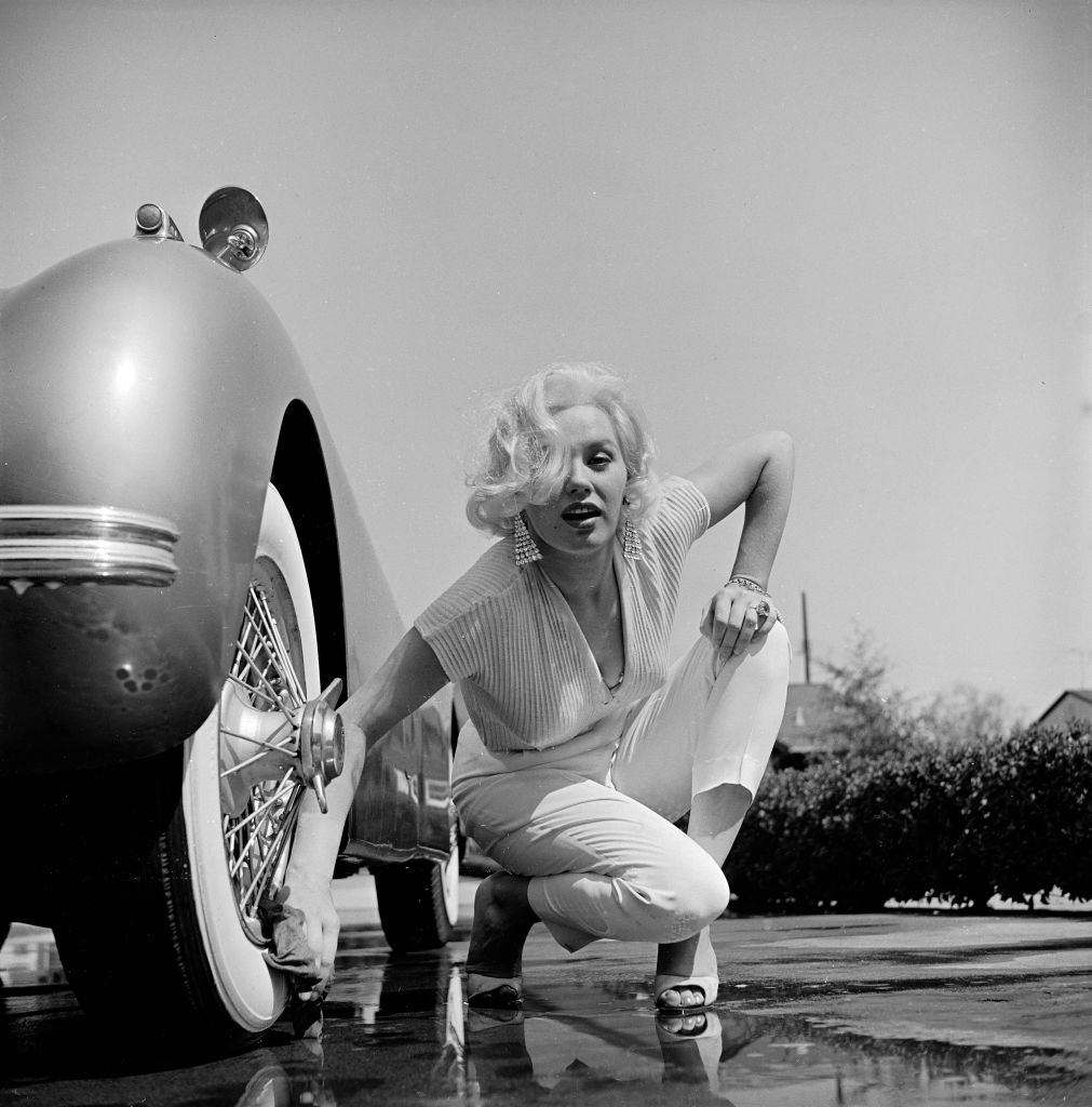 #58 Mamie Van Doren washing the whitewall tires of her Jaguar, 1955.