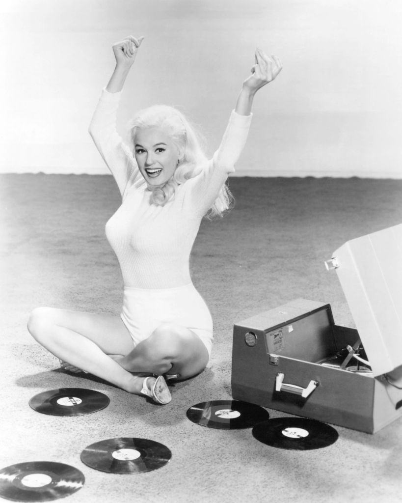 #34 Mamie Van Doren with a record player and a collection of records, 1955.
