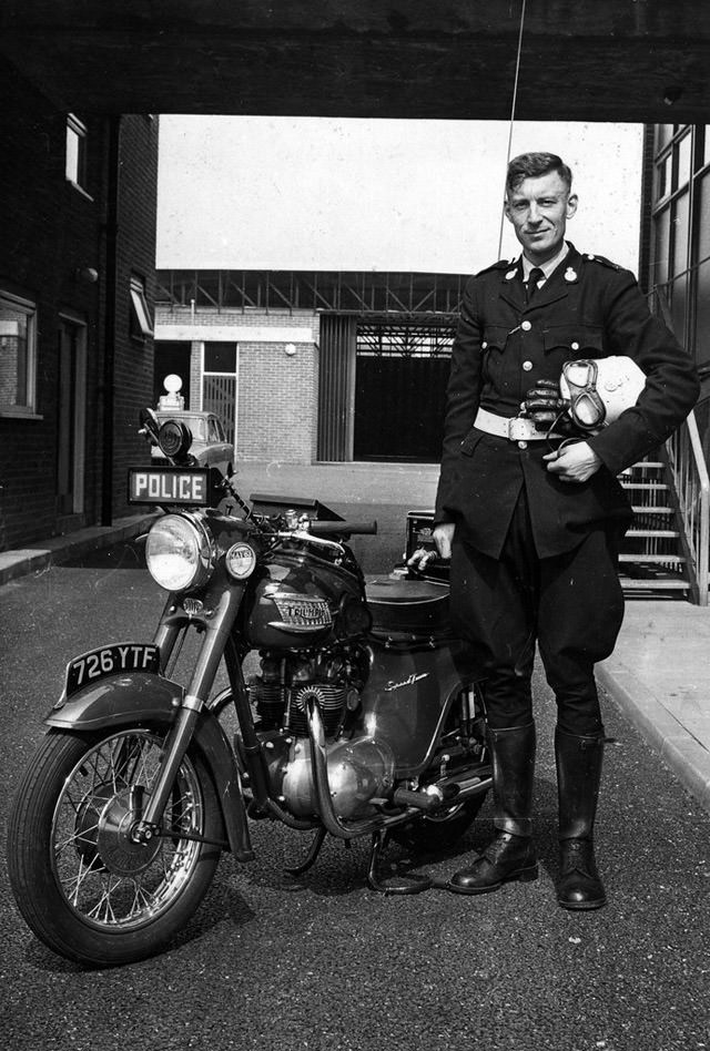 #36 A Lancashire Constabulary motorcyclist stands proudly beside his Triumph machine in the rear yard of Ashton-under-Lyne Police Station in 1963