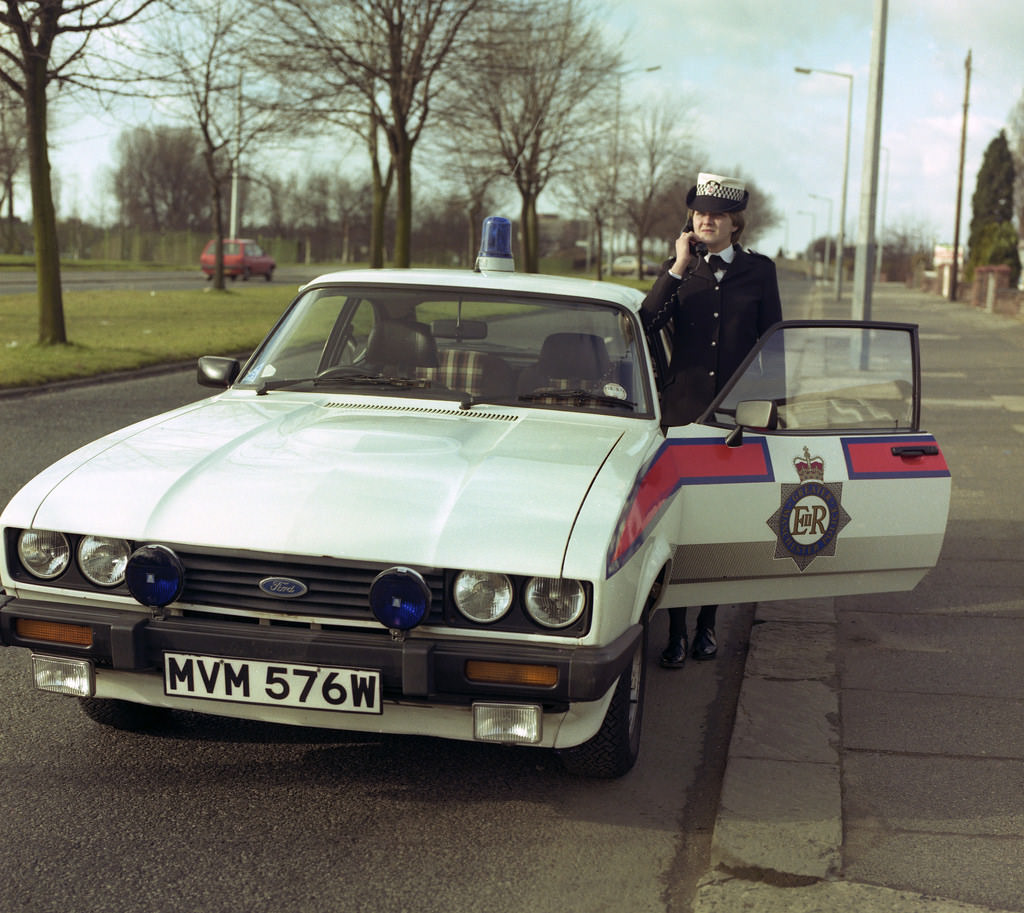 #64 A Greater Manchester Police officer and her Ford Capri vehicle in Chorlton-cum-Hardy in 1982