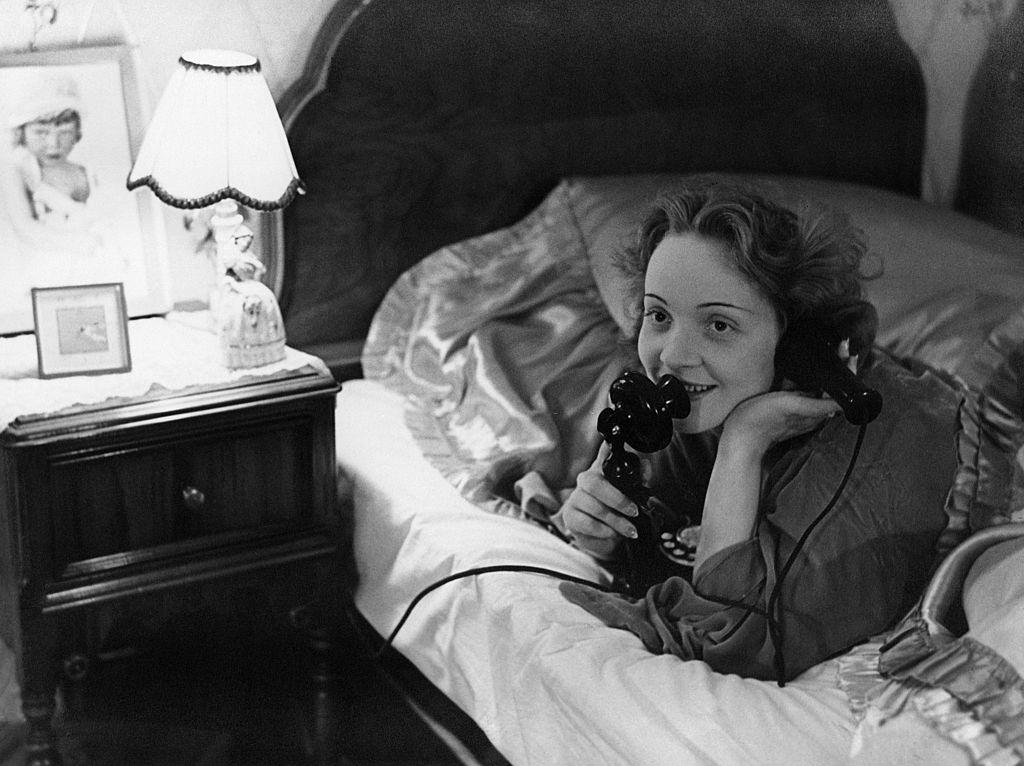 #57 Marlene Dietrich making a telephone call to her daughter from her bed in Hollywood., 1930s