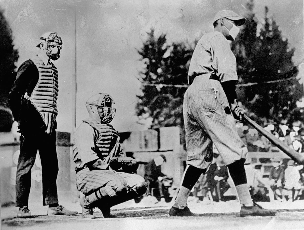 #10 Unident baseball players, one batting & one catching, with umpire standing behind plate, wearing masks which they thought would keep them from getting flu during influenza epidemic of 1918.